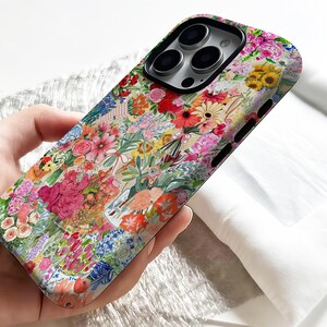 May include: A floral phone case featuring a collage of colorful flowers in shades of pink, red, yellow, and blue. The design includes various flower types, creating a vibrant and artistic pattern. The case is designed to fit a smartphone.