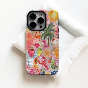 Può includere: Una custodia per telefono colorata con un design a collage tropicale. La custodia presenta illustrazioni di un sole, una palma, frutta e un'aragosta. Il design include la parola "SUNSET" su una grafica a forma di targa. La custodia è appoggiata su una superficie bianca.