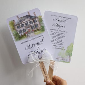 May include: Two wedding program fans with rounded corners, featuring a watercolor illustration of a large house, the text Welcome to the Wedding of Daniel & Harper, and a detailed event timeline. A white sheer ribbon is tied to the wooden handle.