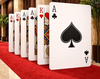 May include: A series of oversized playing cards standing upright on a red carpet. The cards displayed include the Ace of Spades, King of Hearts, Ace of Clubs, Ace of Spades, King of Diamonds, and Ace of Diamonds, each featuring standard suit symbols.