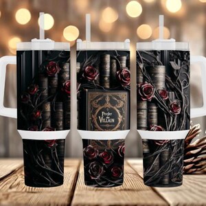 May include: A black tumbler featuring a design of antique books, red roses, and vines. The tumbler has a white handle and lid with a straw. The text "Prefer Villain" is visible on the front of the tumbler.