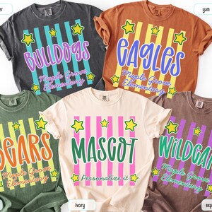 May include: Five short-sleeve t-shirts in pepper, yam, moss, ivory, and espresso colors. Each shirt features vertical stripes, yellow stars, and text including school names like Bulldogs, Eagles, Bears, Mascot, and Wildgats, plus Maple Grove Elementary.
