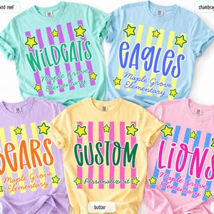 May include: Five short-sleeve t-shirts in island reef, chambray, orchid, butter, and blossom colors. Each shirt features vertical stripes, yellow stars, and text including Wildgats, Eagles, Bears, Gustom, and Lions with Maple Grove Elementary.