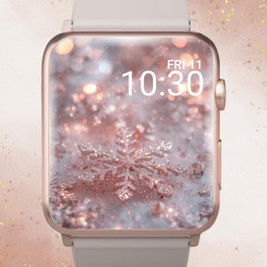 Puede incluir: Un reloj inteligente en oro rosa con una correa gris claro. La pantalla muestra un diseño de copo de nieve sobre un fondo brillante. La hora es 10:30 AM del viernes. Las palabras "In Bloom Babe" están en la parte superior.