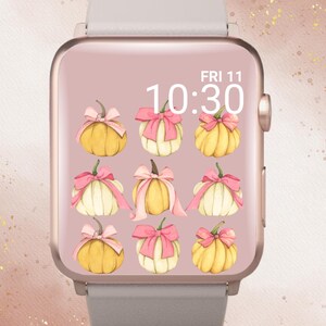 May include: A rose gold smartwatch with a light grey strap shows a pumpkin-themed watch face. The watch face features nine watercolour pumpkins with pink bows. The time is 10:30 on Friday, the 11th. The text "In Bloom Babe" is at the top.