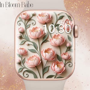 Peut inclure: Une montre connectée avec un bracelet beige clair et un boîtier or rose affichant des pivoines roses avec des tiges et des feuilles vertes sur fond crème. L'écran affiche le texte In Bloom Babe, la date FRI 11 et l'heure 10:30.