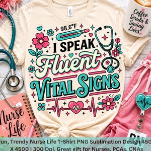 May include: A cream-colored t-shirt featuring a graphic with the text I SPEAK Fluent VITAL SIGNS, a thermometer reading 98.6°F, a stethoscope, pink flowers, and a heart rhythm line. The design uses teal, pink, and black colors on the fabric.