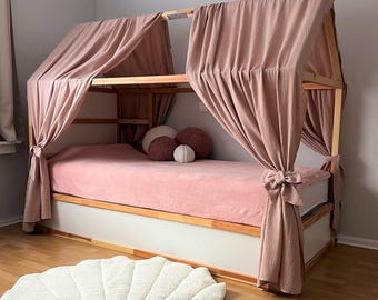 May include: A wooden framed bed with a canopy draped in dusty rose fabric. The bed has a pink mattress and decorative pillows. A white seashell-shaped rug sits on the wooden floor in front of the bed.