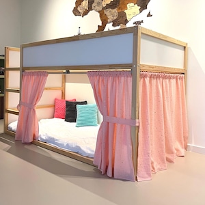 May include: A wooden bunk bed with a light wood frame, white panels, and pink curtains. The bed is decorated with colorful pillows and a wooden map of Ukraine on the wall.