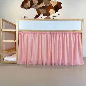 Pode incluir: Uma cama de beliche de madeira com uma cortina rosa claro. A cama tem uma escada e uma pequena &aacute;rea de cama. Um mapa de madeira da Ucr&acirc;nia est&aacute; montado na parede acima da cama.