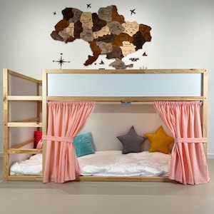 May include: A wooden bunk bed with a light wood frame, featuring a ladder and pink curtains. The bed is decorated with star-shaped pillows and a map of Ukraine on the wall. The bed has a white mattress.