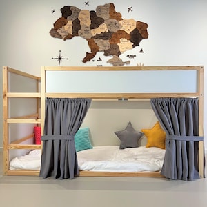 May include: A wooden bunk bed with a natural finish, featuring a ladder and gray curtains. The bed is decorated with star-shaped and rectangular pillows in gray, yellow, and turquoise. A wooden map of Ukraine hangs on the wall above the bed.