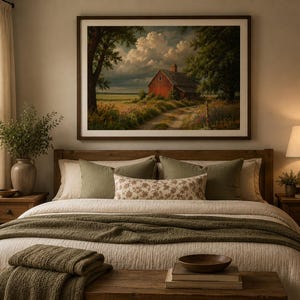 May include: A framed landscape wall art print featuring a red barn situated in a grassy field under a cloudy sky, displayed above a wooden bed frame with a white quilt, olive green throw blanket, and decorative pillows in a bedroom setting.