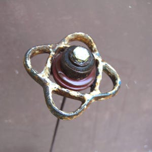 May include: Close-up of a vintage, rusty metal valve handle. The handle has a four-petal design with a central, layered mechanism. The colors are primarily brown, with hints of blue and white from the rust.