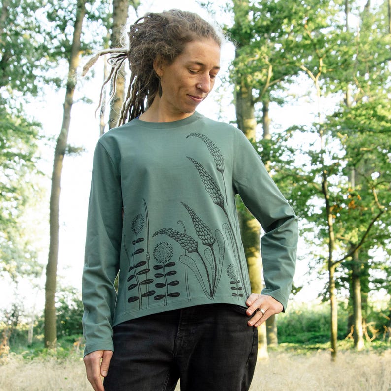 May include: A teal long-sleeved shirt with a black floral print. The print features stylised flowers and leaves.