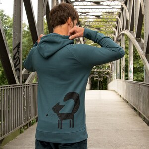 May include: A teal blue hooded sweatshirt with a black fox graphic on the back.