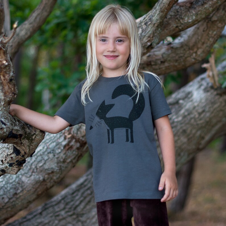 May include: A young person wearing a charcoal grey t-shirt with a black and white graphic of a fox on the front. The fox is looking to the left and has a long tail.