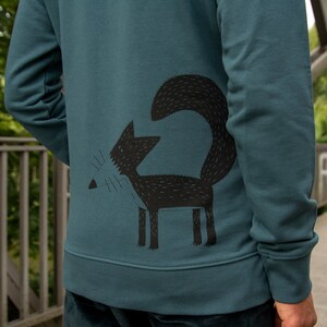May include: A teal blue sweatshirt with a black graphic of a stylized fox on the back.