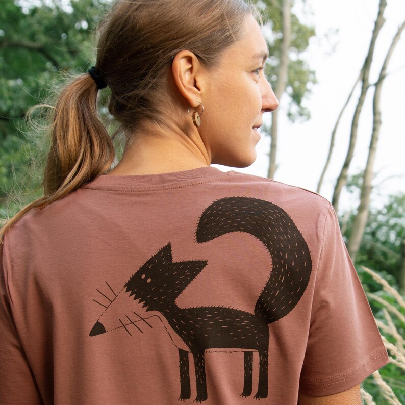 May include: A mauve t-shirt with a black and white illustration of a fox on the back.