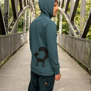 May include: A teal blue hooded sweatshirt with a black fox graphic on the back. The fox is stylized with a long, curled tail.