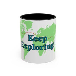 May include: White ceramic mug with a black interior. The mug features a green world map design with a red dotted line and the words "Keep Exploring!" in teal lettering. A travel-themed gift.