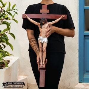 May include: A dark brown wooden crucifix featuring a detailed figure of Jesus with a crown of thorns, a white loincloth, and visible wounds. A small rectangular plaque with Hebrew text is attached to the upper vertical beam of the cross.