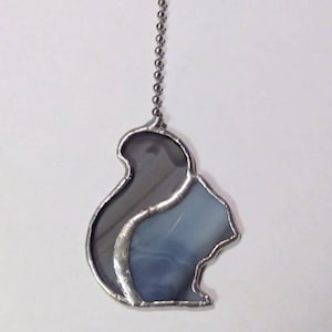 May include: A stained glass squirrel pull chain for a light fixture. The squirrel is made of gray and blue glass and is outlined in silver.