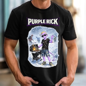 Puede incluir: Camiseta negra con el texto "PURPLE RICK" en un diseño morado y blanco. La camiseta presenta un gráfico de un personaje de dibujos animados morado asando a la parrilla en una escena nevada. El personaje lleva gafas de sol y pantalones cortos vaqueros.