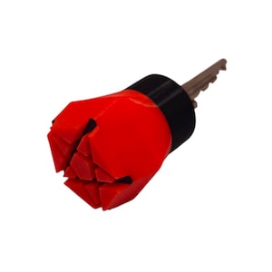 Op de afbeelding: Een rood en zwart sleutelvormig gereedschap met een bruine sleutel eraan. Het gereedschap heeft een geometrisch ontwerp met een rode, hoekige kop en een zwarte band. De sleutel is een standaardmaat.