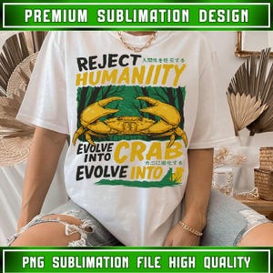 Puede incluir: Camiseta blanca con un diseño de cangrejo amarillo y el texto "REJECT HUMANITY, EVOLVE INTO CRAB". El diseño incluye texto japonés y un fondo de bosque verde. Es un diseño de sublimación premium.
