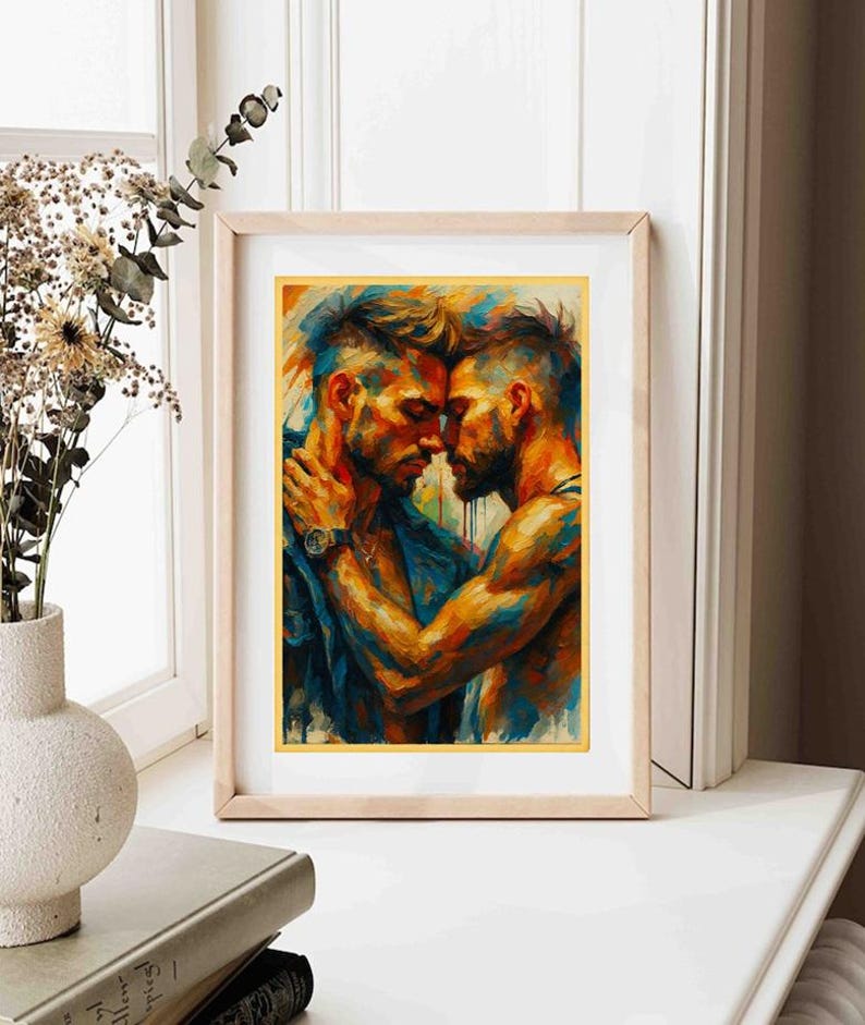 May include: A framed art print depicting an abstract painting of two men in an embrace. The artwork uses a vibrant palette of blues, oranges, and yellows. The men are shown close together, suggesting intimacy. The frame is a light wood colour.