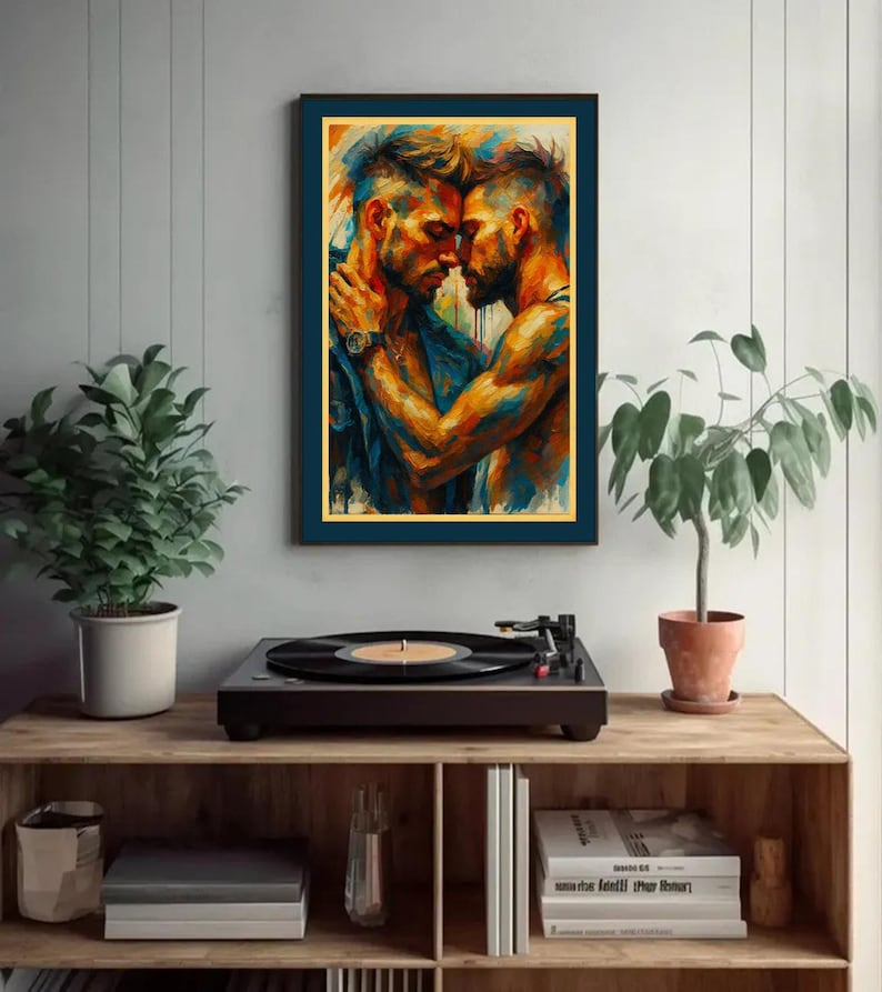 May include: A colourful framed print showing two men in an embrace, with shades of orange, blue, and yellow. The artwork hangs above a wooden shelf with a record player, plants, and books. The scene has a modern, artistic feel.
