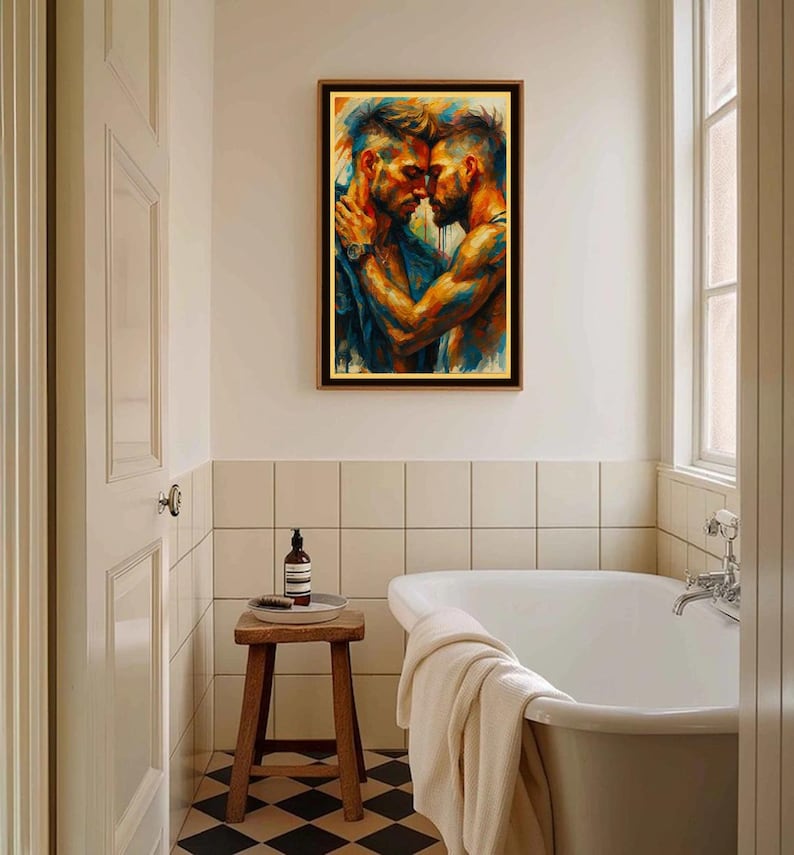 May include: A framed artwork showing two men in an embrace, painted with vivid blues, oranges, and yellows. The print is displayed above a wooden stool in a bathroom, with a white bathtub and a black and white tiled floor.