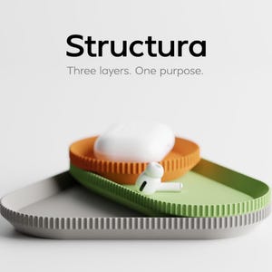 May include: A product display featuring three colorful, layered trays. The top tray is orange, the middle is green, and the bottom is gray. A white earbud case and a single earbud rest on the trays. The word "Structura" is displayed above the trays.