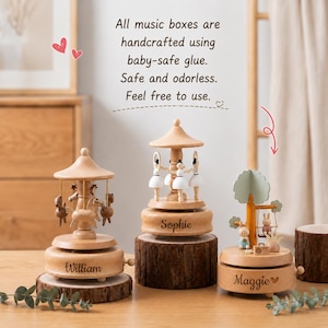 May include: Three wooden music boxes with natural finishes. The left features horses, the center features ballerinas, and the right features rabbits on a swing. Each base is engraved with names: William, Sophie, and Maggie. Text reads: All music boxes are handcrafted using baby-safe glue. Safe and odorless. Feel free to use.