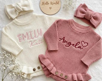 Può includere: Due completi per neonati: un body in maglia avorio con "Emily Kate" ricamato in rosa e un body rosa con "Angela" ricamato. Entrambi hanno volant e bottoni in legno. Fasce abbinate e un cartello di legno "Hello World".