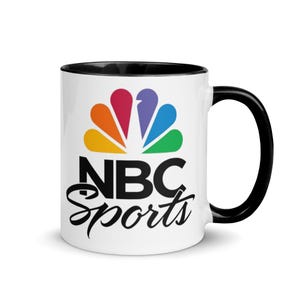 May include: White ceramic mug with a black interior and handle. The mug features the NBC Sports logo in black, with the iconic peacock logo in vibrant colors. The words "NBC Sports" are written in a stylish script font.