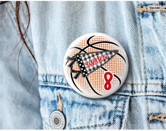 May include: A round pinback button featuring a basketball graphic with orange dots and black lines. A black and white buffalo plaid pennant is centered with the word eagles in red script. The number 8 is printed in red below the pennant.