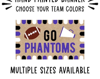 May include: A rectangular banner with a tan background featuring the text GO PHANTOMS in purple, a brown football, and a white megaphone. The border has a repeating pattern of black and purple semi-circles. Text reads HAND PAINTED BANNER CHOOSE YOUR TEAM COLORS and MULTIPLE SIZES AVAILABLE.