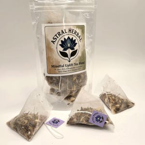 May include: A clear plastic bag of tea bags with the text "ASTRAL HERBAL" and "Mindful Uplift Tea Blend". The tea bags are filled with a blend of herbs and spices. Three individual tea bags are also visible.