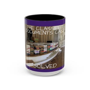 Peut inclure: Mug en céramique blanche avec intérieur noir et une bande violette en haut et en bas. La tasse présente une image de boîtes étiquetées "Epstein Files" et le texte "The Classified Documents Case SOLVED."