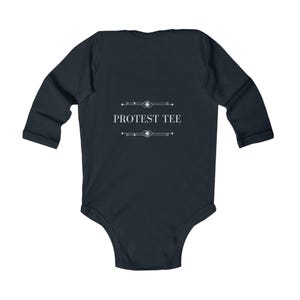 K&ouml;nnte beinhalten: Dunkelmarinefarbener Baby-Body mit langen &Auml;rmeln und dem wei&szlig;en Text "PROTEST TEE". Der Text ist zentriert und von dekorativen Linien umrahmt. Der Body ist f&uuml;r S&auml;uglinge und Kleinkinder konzipiert.