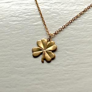 May include: A gold chain necklace with a four-leaf clover pendant.