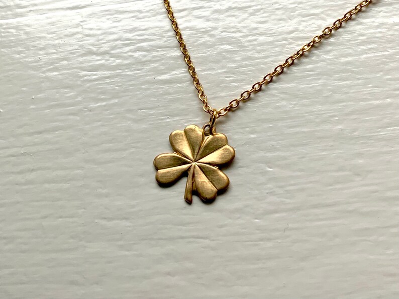 May include: A gold chain necklace with a four-leaf clover pendant.