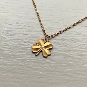 May include: A gold chain necklace with a four-leaf clover pendant.