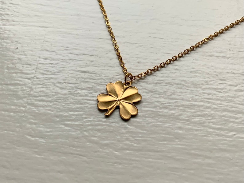 May include: A gold chain necklace with a four-leaf clover pendant.