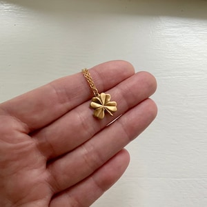 May include: A gold four-leaf clover pendant necklace on a delicate chain.