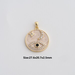 May include: Gold-toned pendant with a celestial design. The round pendant features a cream-colored background with a star, crescent moon, and an eye. The eye is detailed with a black center and surrounding crystals. The pendant measures 27.6x20.7x2.5mm.