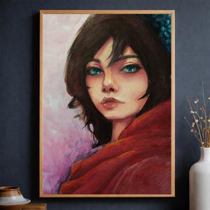 Puede incluir: Retrato al óleo de una mujer con cabello oscuro y llamativos ojos turquesa. Lleva una capa roja y la obra está enmarcada en un marco de madera marrón claro. El fondo tiene suaves tonos rosas y morados.