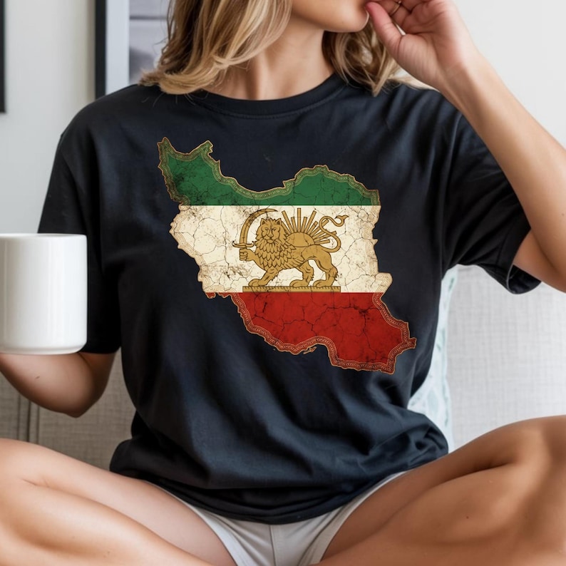 Puede incluir: Camiseta negra con un gr&aacute;fico desgastado de la bandera iran&iacute; en forma de mapa. El dise&ntilde;o de la bandera incluye rayas verdes, blancas y rojas, con un emblema de le&oacute;n y sol dorado en el centro. Es una prenda de vestir informal.